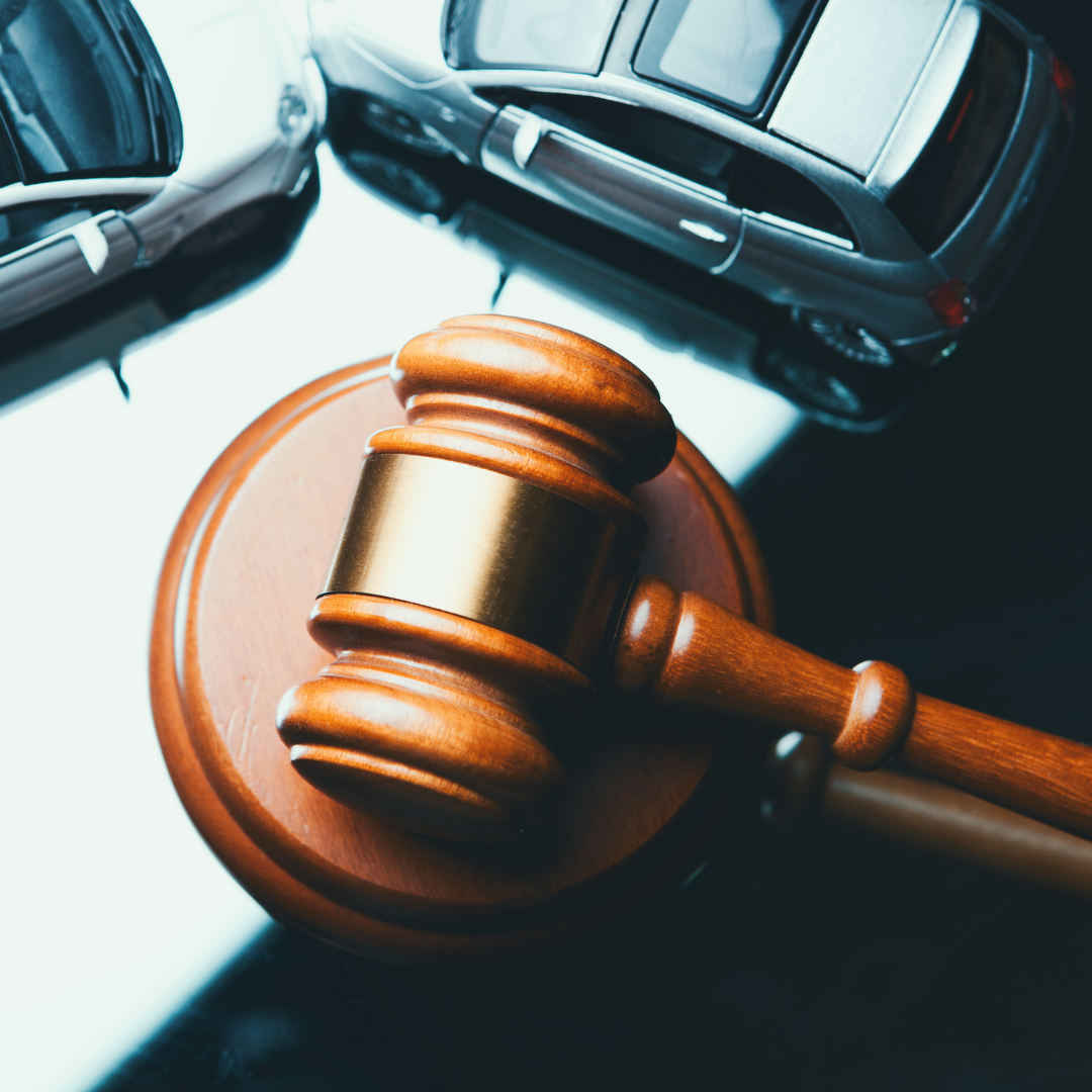 Um malhete ao lado de dois carros pequenos